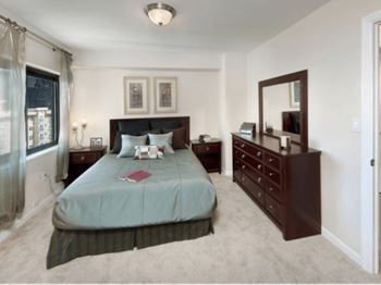 A bedroom with a bed, nightstand, and dresser at Skye at Belltown Apartments, Seattle, WA